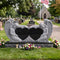 Double heart headstone with two carved angels displayed in a cemetery setting