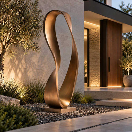 Abstract bronze ribbon sculpture with a flowing loop in a modern outdoor garden