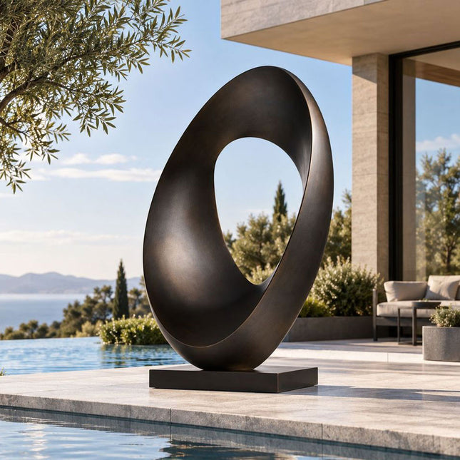 Abstract bronze ring sculpture with a twisted oval form beside a modern pool