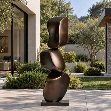 Abstract bronze sculpture with stacked balancing forms in a contemporary courtyard