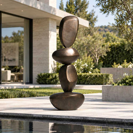 Abstract bronze sculpture with stacked pebble forms in a modern outdoor setting
