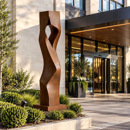 Abstract Corten steel sculpture with a tall twisted form at a modern building entrance