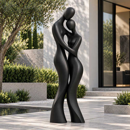 Matte black bronze couple sculpture displayed beside a swimming pool overlooking the ocean