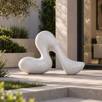 Abstract white marble sculpture with a rounded organic form in a modern courtyard