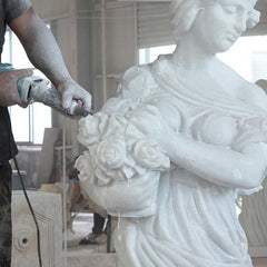 A master artisan hand carving a white marble sculpture to refine its proportions and artistic form.