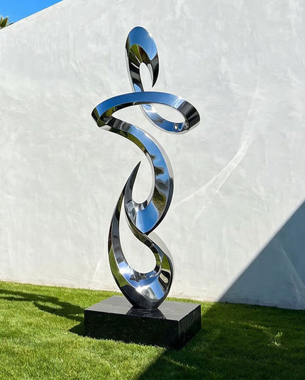 Contemporary stainless steel abstract sculpture installed in a modern garden landscape