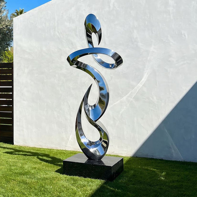 Contemporary stainless steel abstract sculpture installed in a modern garden landscape