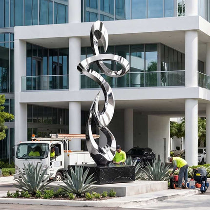 Large stainless steel abstract sculpture installed at a contemporary architectural entrance