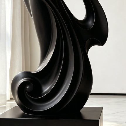 Detail view of matte black painted stainless steel sculpture with curved flowing form