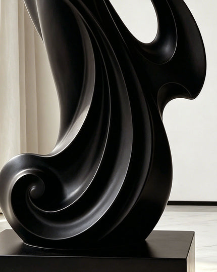 Detail view of matte black painted stainless steel sculpture with curved flowing form