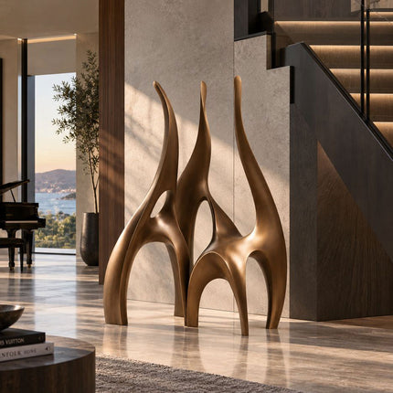 Large abstract bronze sculpture with open arches displayed beside a modern staircase
