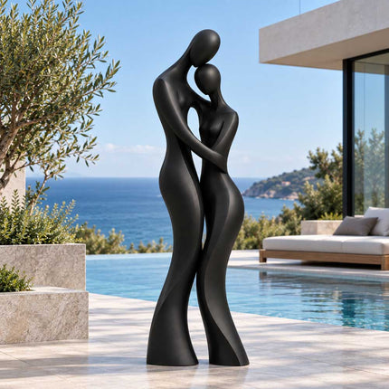 Matte black bronze couple sculpture displayed beside a swimming pool overlooking the ocean