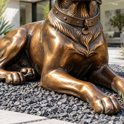 Close-up of the sculpted chest fur and extended front paws of a reclining bronze dog statue.