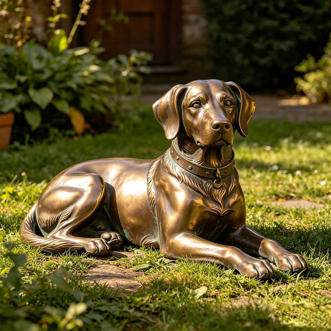 Bronze dog statue resting on the grass in a landscaped private garden.