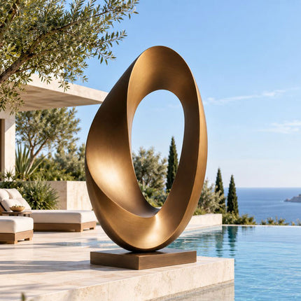 Abstract bronze loop sculpture on a rectangular base beside a swimming pool at a modern home.