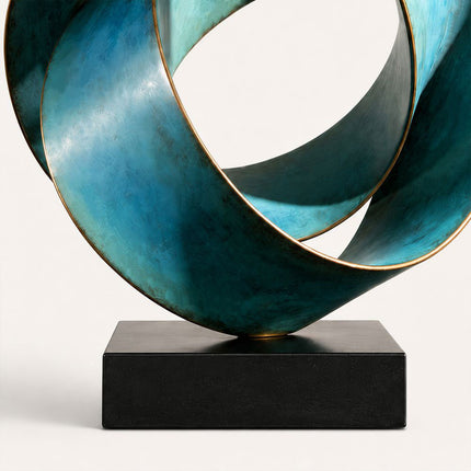 Close-up of overlapping blue-green bronze ribbons with warm bronze edges above a black rectangular base
