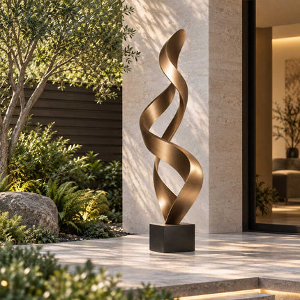 Tall bronze ribbon sculpture with two openings beside the entrance of a modern home