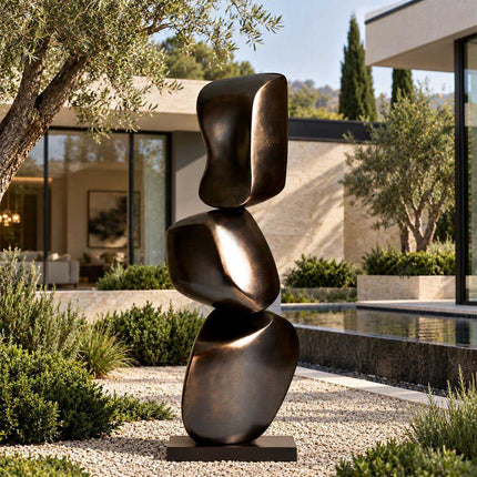 Stacked abstract bronze sculpture displayed in a modern garden beside a reflecting pool
