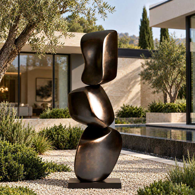 Stacked abstract bronze sculpture displayed in a modern garden beside a reflecting pool