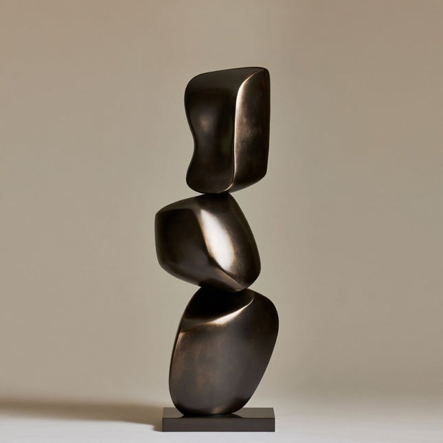Bronze sculpture art with three rounded forms balanced vertically on a rectangular base