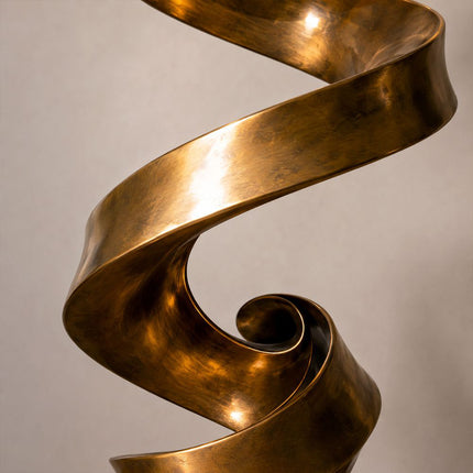 Close-up of the tightly curled ribbon form and warm bronze patina