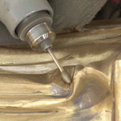 Artisan refining the surface details of a bronze sculpture before patination