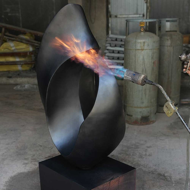 Applying heat to develop a handcrafted patina on a bronze sculpture surface