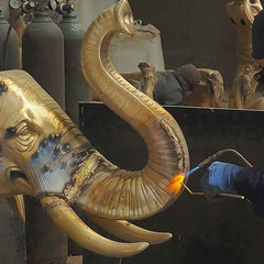 Artisan welding bronze sculpture components during the assembly process