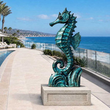 Bronze seahorse sculpture with blue-green patina displayed on a light stone pedestal beside a coastal residential swimming pool