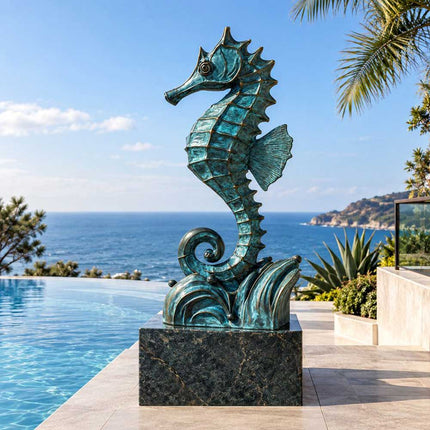 Blue patina bronze seahorse sculpture displayed on a dark stone pedestal beside a residential infinity pool overlooking the ocean