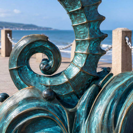 Close-up of the curled tail and sculpted wave base of a blue-green patina bronze seahorse sculpture