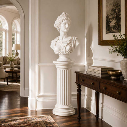 Classical female marble bust displayed on a fluted pedestal in an elegant interior