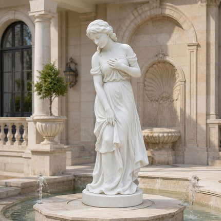 Classical marble female statue displayed beside a residential courtyard water feature