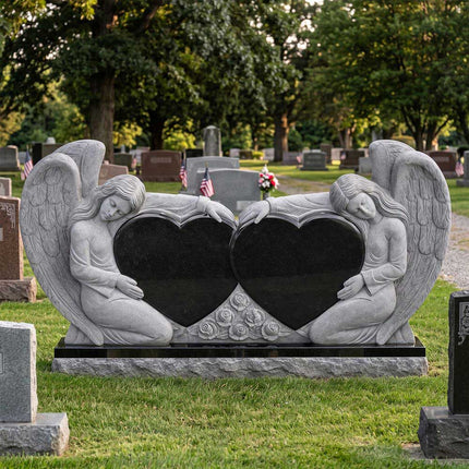 Double heart companion headstone with carved angels and roses in a cemetery