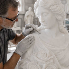 An experienced artisan carefully inspecting a finished white marble sculpture before final approval and delivery.