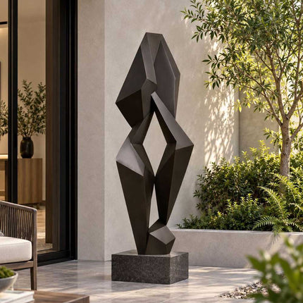 Geometric abstract bronze sculpture with faceted forms in a modern residential courtyard