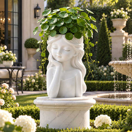 White girl head planter with trailing greenery displayed on a stone pedestal in a landscaped garden