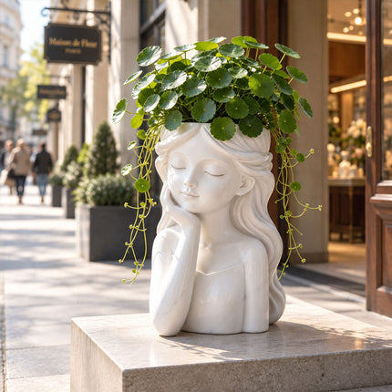 White girl head planter filled with green foliage displayed on a stone ledge outside a storefront
