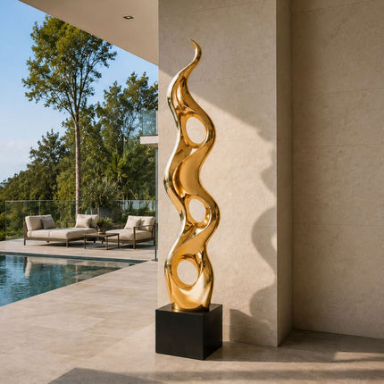 Tall gold abstract sculpture displayed beside a modern architectural wall and pool