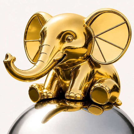 Close-up of a golden elephant sculpture with raised trunk, oversized ears, and polished metal finish