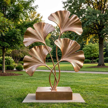 Gold stainless steel ginkgo sculpture installed in a landscaped garden setting