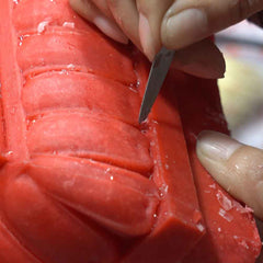 Craftsman refining fine details on a wax sculpture model for lost-wax casting