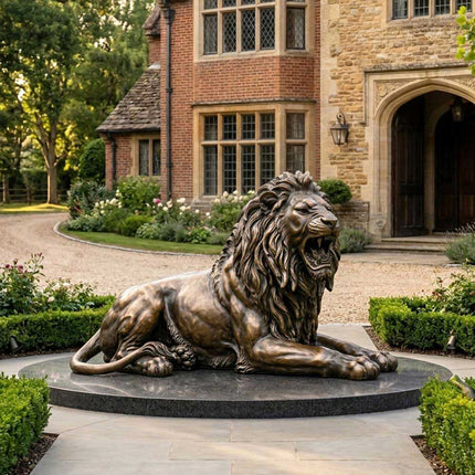 Reclining bronze lion statue displayed in a landscaped estate garden