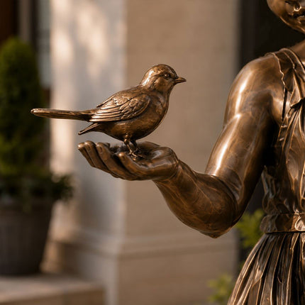 Close-up detail of bronze bird held by girl sculpture