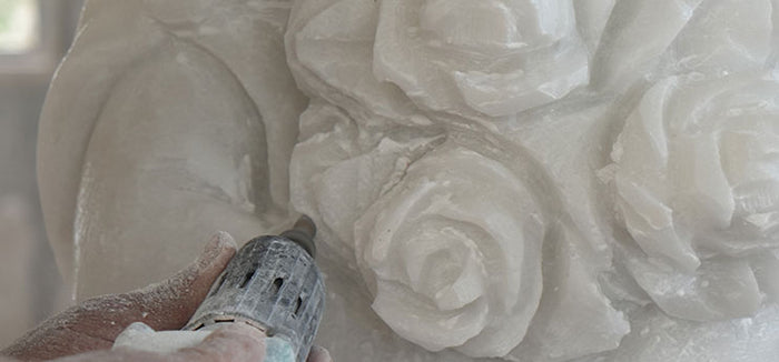 A master artisan hand carving intricate marble details using traditional sculpting techniques.