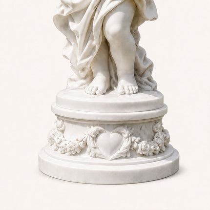 Marble angel statue detail with floral ornament and heart motif on the base