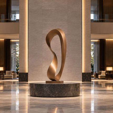 Tall minimalist bronze sculpture presented on a circular stone platform in a spacious modern lobby.