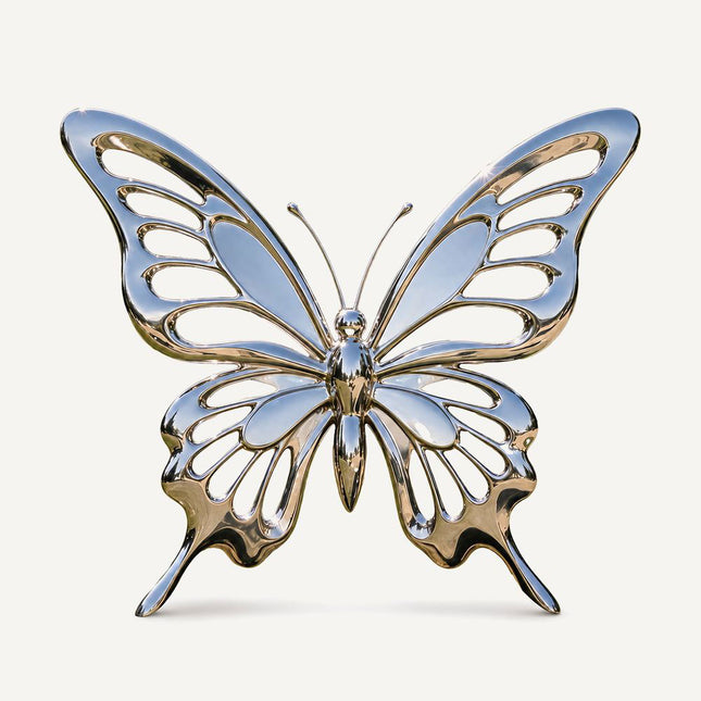 Mirror polished stainless steel butterfly sculpture with symmetrical openwork wings on a white background.