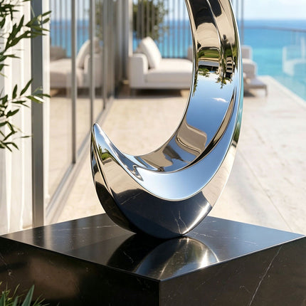 Detail view of polished stainless steel sculpture with black stone base