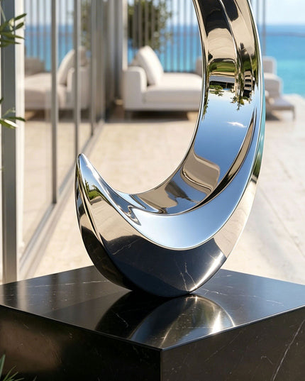 Detail view of polished stainless steel sculpture with black stone base